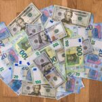 Aerial view of mixed Euro and US Dollar banknotes on a wooden floor, symbolizing global finance.