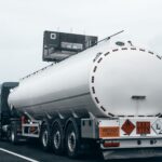 Rear view of a large tanker truck transporting fuel on a highway, emphasizing logistics and transportation.