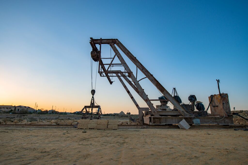 Rusty crane at an industrial site during sunset, highlighting its aged machinery.