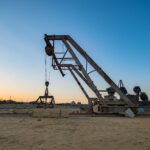 Rusty crane at an industrial site during sunset, highlighting its aged machinery.
