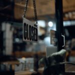 Close-up of a closed sign hanging on a glass door at night, with blurred indoor view.