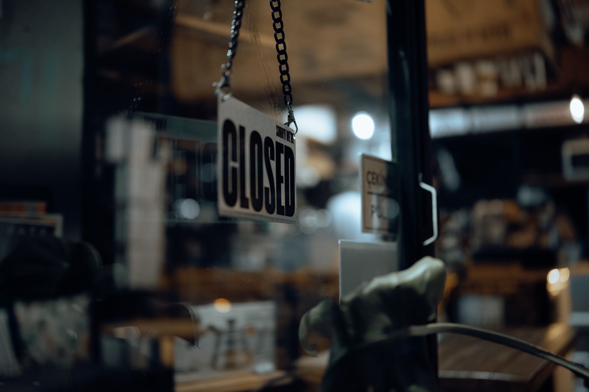 Close-up of a closed sign hanging on a glass door at night, with blurred indoor view.