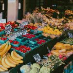 Colorful fruit and vegetable market stall displaying a variety of fresh produce with visible price tags.