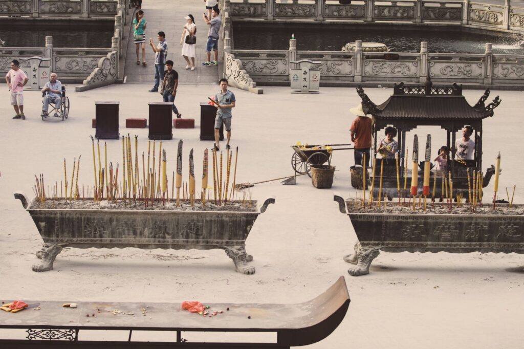 People engaging in a traditional ceremony with incense sticks at a temple.