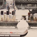 People engaging in a traditional ceremony with incense sticks at a temple.