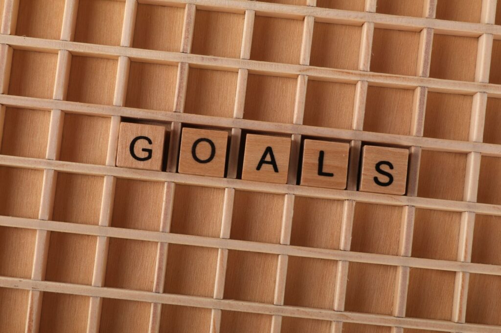 Wooden alphabet tiles spelling 'GOALS' on a grid background, symbolizing aspirations.
