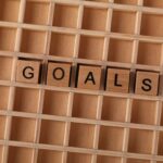 Wooden alphabet tiles spelling 'GOALS' on a grid background, symbolizing aspirations.