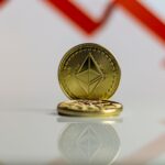 Close-up of Ethereum cryptocurrency with red downward arrow, symbolizing market decline.