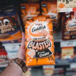Close-up of hand holding Goldfish Flavour Blasted Xtreme Cheddar snack in a grocery store.