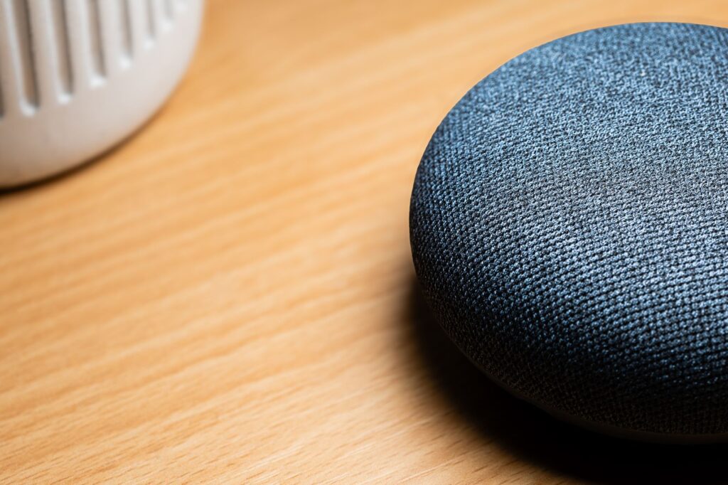A close-up view of a smart speaker on a wooden table, capturing texture details.