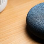 A close-up view of a smart speaker on a wooden table, capturing texture details.