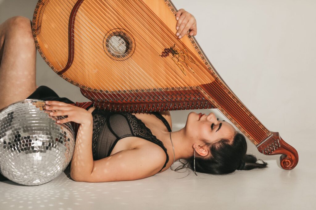 Fashionably artistic pose with a model holding a disco ball and a musical instrument.