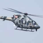A camouflaged Indian Air Force helicopter in flight at Bengaluru air show.