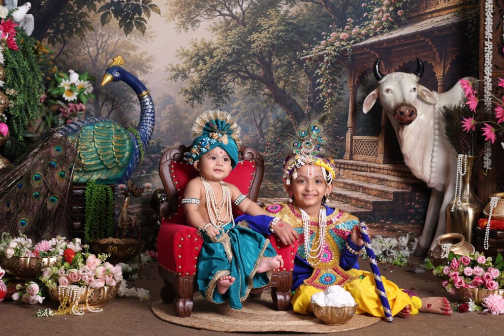 Children dressed as Krishna for Janmashtami celebration with cow and peacock decor.