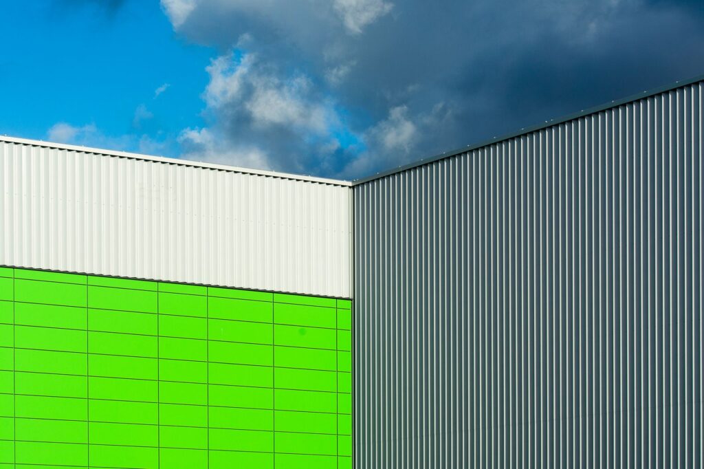 Close-up of a modern building facade with colorful panels and corrugated metal against a dramatic blue sky.
