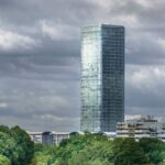 The Highlight Tower in Munich rises against a backdrop of dramatic clouds, capturing urban architecture.