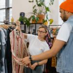 A woman helps a man choose a shirt in a modern clothing store.