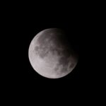 Close-up shot of a lunar eclipse, showcasing the moon's surface with shadow play.