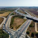 Aerial view capturing a busy highway intersection surrounded by agricultural fields and open landscape.