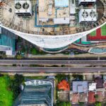 Drone shot capturing Jakarta's urban skyline with high-rise buildings, roads, and green areas.