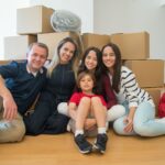 A joyful family sitting together with moving boxes in their new home.