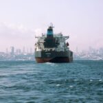 Large cargo ship sails through Istanbul's Bosphorus with city skyline in background.