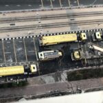 Aerial shot of yellow fire trucks in a city street responding to an emergency.