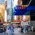 Bustling street in Times Square, NYC with diverse people and vibrant cityscape.