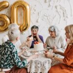 Senior women joyfully celebrating a 60th birthday with cake and decorations.