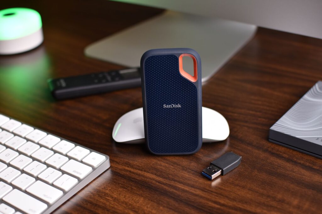 Close-up of a desk setup featuring a SanDisk SSD, keyboard, and USB drive, highlighting modern technology.