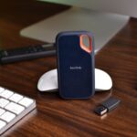 Close-up of a desk setup featuring a SanDisk SSD, keyboard, and USB drive, highlighting modern technology.