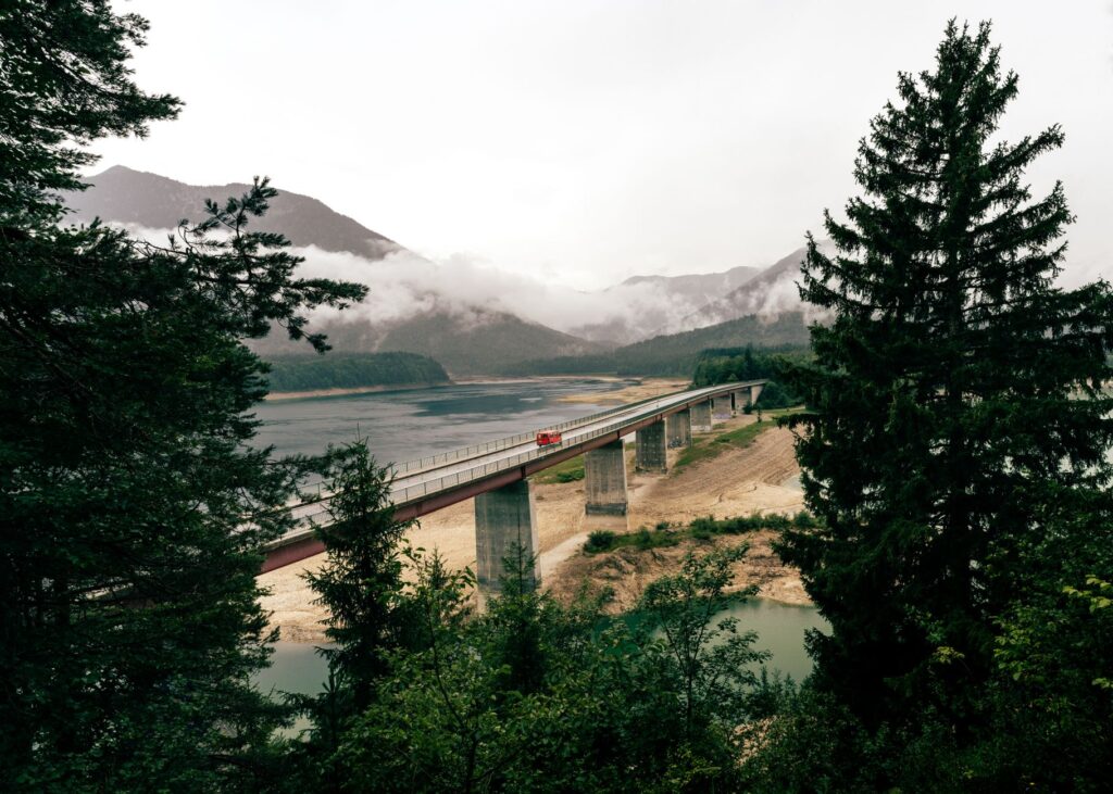Breathtaking view of the Sylvenstein Dam bridge against misty mountains in Lenggries, Germany.