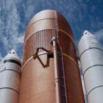 Dramatic view of rocket boosters against a bright blue sky, showcasing aerospace technology.