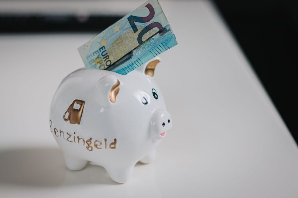 A white piggy bank with a €20 note inserted, symbolizing savings.