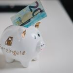 A white piggy bank with a €20 note inserted, symbolizing savings.