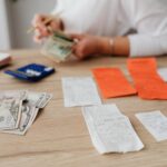 A person using a calculator and cash to plan a household budget.