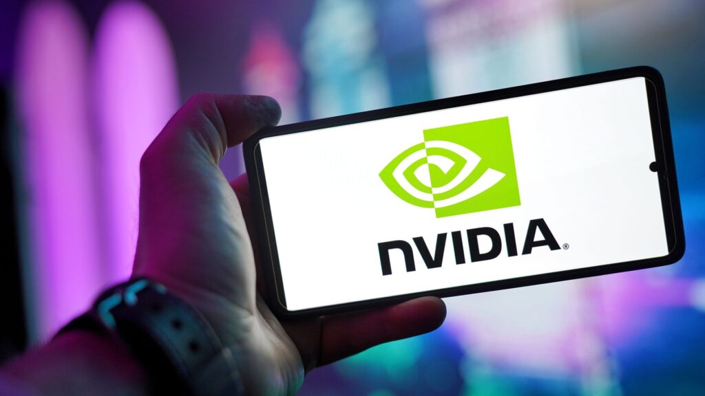 Close-up of a hand holding a smartphone showing the NVIDIA logo on screen with a blurred background.