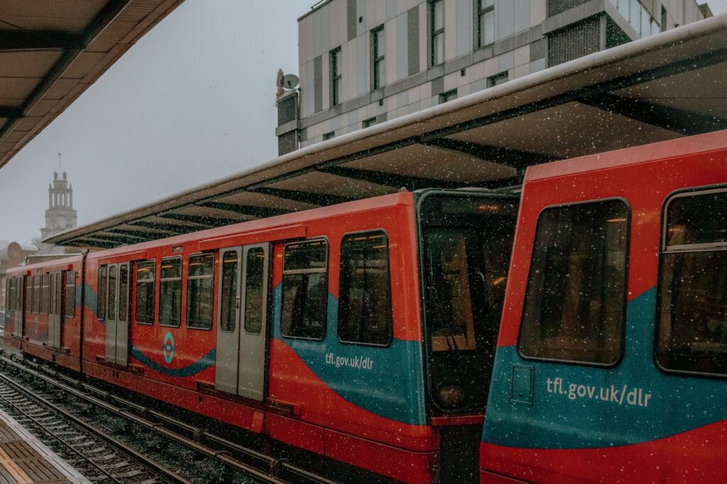 Red train at an urban station, signifying city travel and public transport.