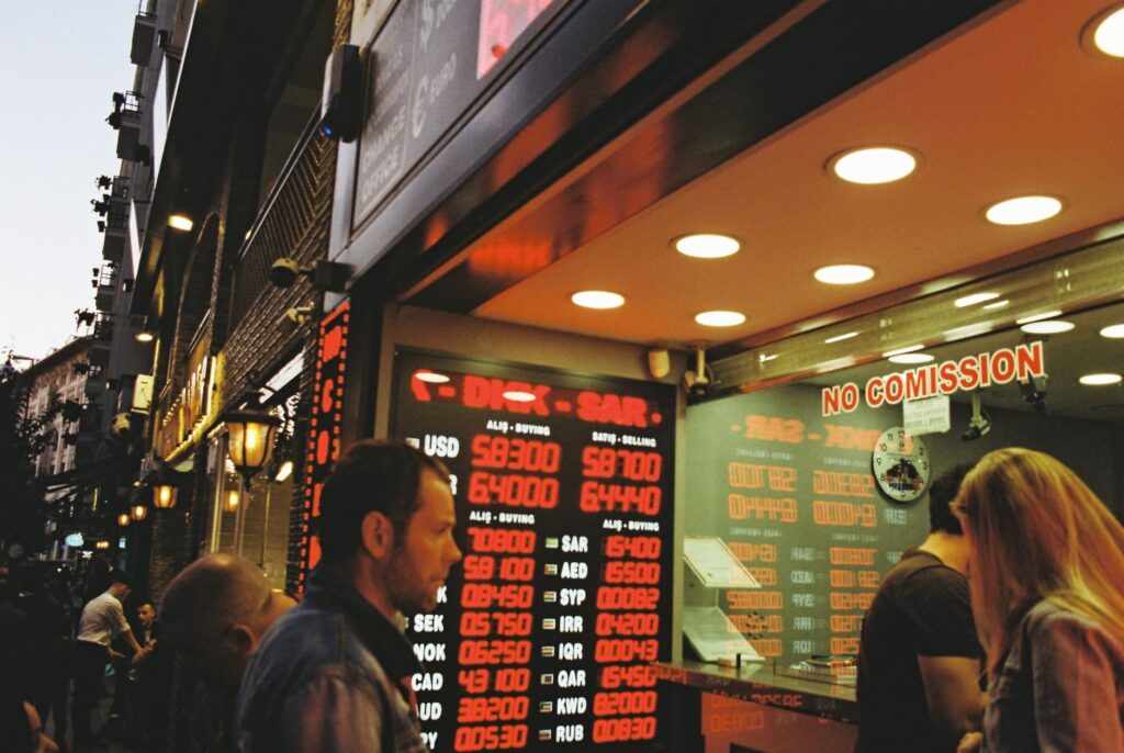 People gathering at a currency exchange office on a busy city street during dusk.