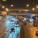 Traffic flows along a major Beijing highway, illuminated by bright streetlights at night.