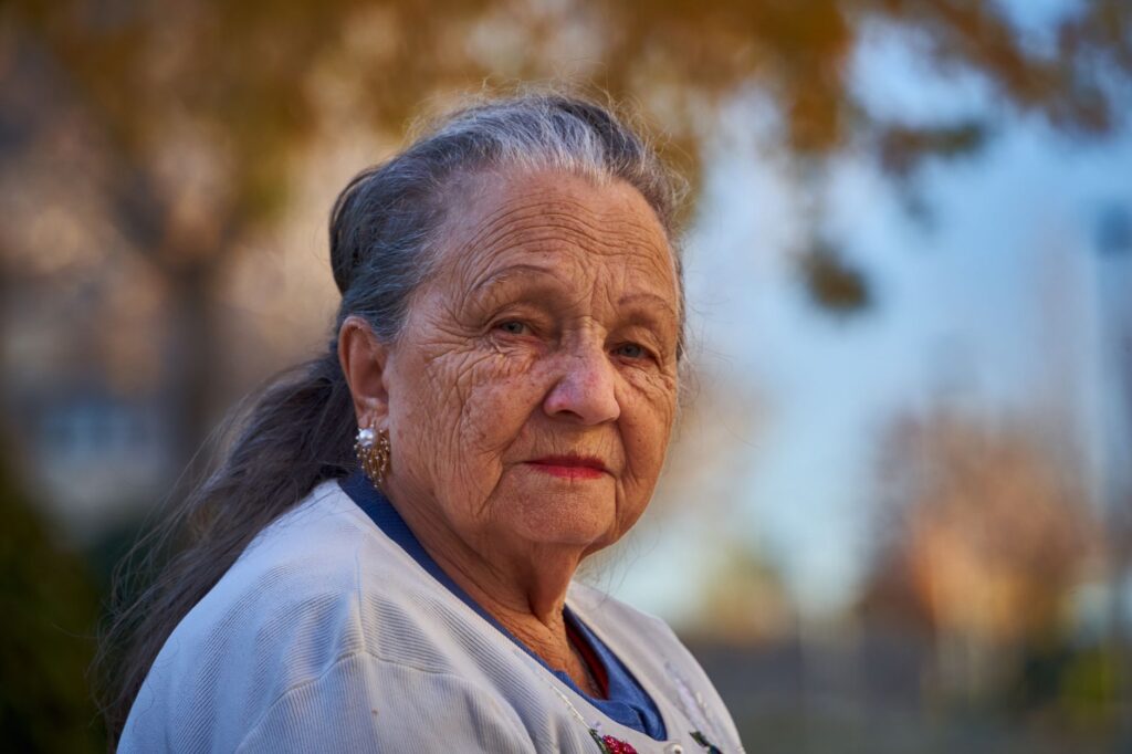 Senior woman with thoughtful expression in a sunny outdoor setting.