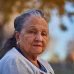 Senior woman with thoughtful expression in a sunny outdoor setting.