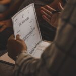 Close-up of a person holding a wedding certificate in a formal ceremony setting.