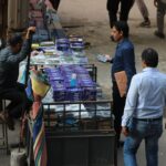 Men browsing mobile accessories at a street market stall.