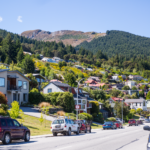 Vibrant suburban street in Queenstown, New Zealand, nestled against lush mountains.