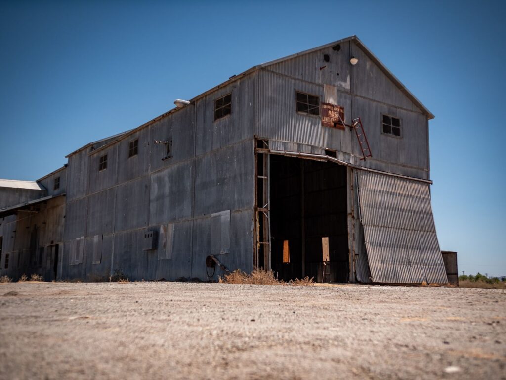 Rustic abandoned warehouse in Arizona with open doors under a clear blue sky.