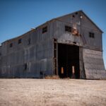 Rustic abandoned warehouse in Arizona with open doors under a clear blue sky.