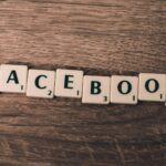 Scrabble tiles spelling 'Facebook' on a wood background, symbolizing social media.