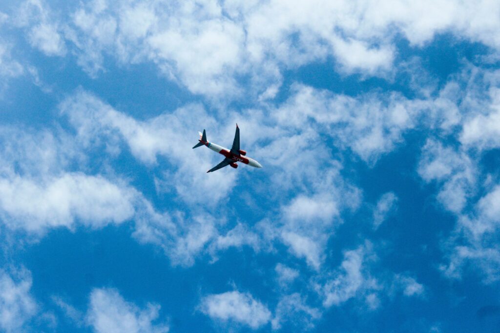 Jet flying through bright blue sky scattered with white clouds, providing a sense of travel adventure.