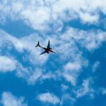 Jet flying through bright blue sky scattered with white clouds, providing a sense of travel adventure.